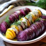 The image you uploaded showcases beautifully roasted Hasselback beets, featuring both red and golden varieties. The beets are sliced thinly in the traditional Hasselback style, allowing them to fan out while roasting, which not only adds visual appeal but also enhances flavor absorption. The dish is garnished with fresh dill and drizzled with a creamy dill dressing, highlighting the earthy sweetness of the beets paired with the tangy, herbaceous notes of the dill. Key Features of the Dish: